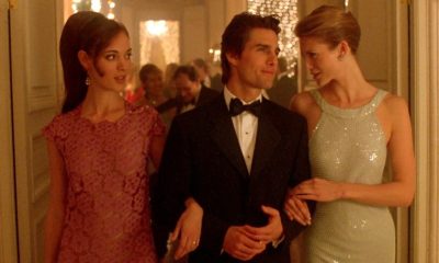 Actor Tom Cruise in Eyes Wide Shut, wearing a tuxedo, arm in arm with two women